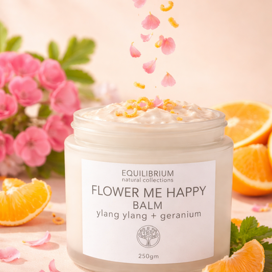 Balm jar labeled 'Flower Me Happy' with flowers and oranges in the background